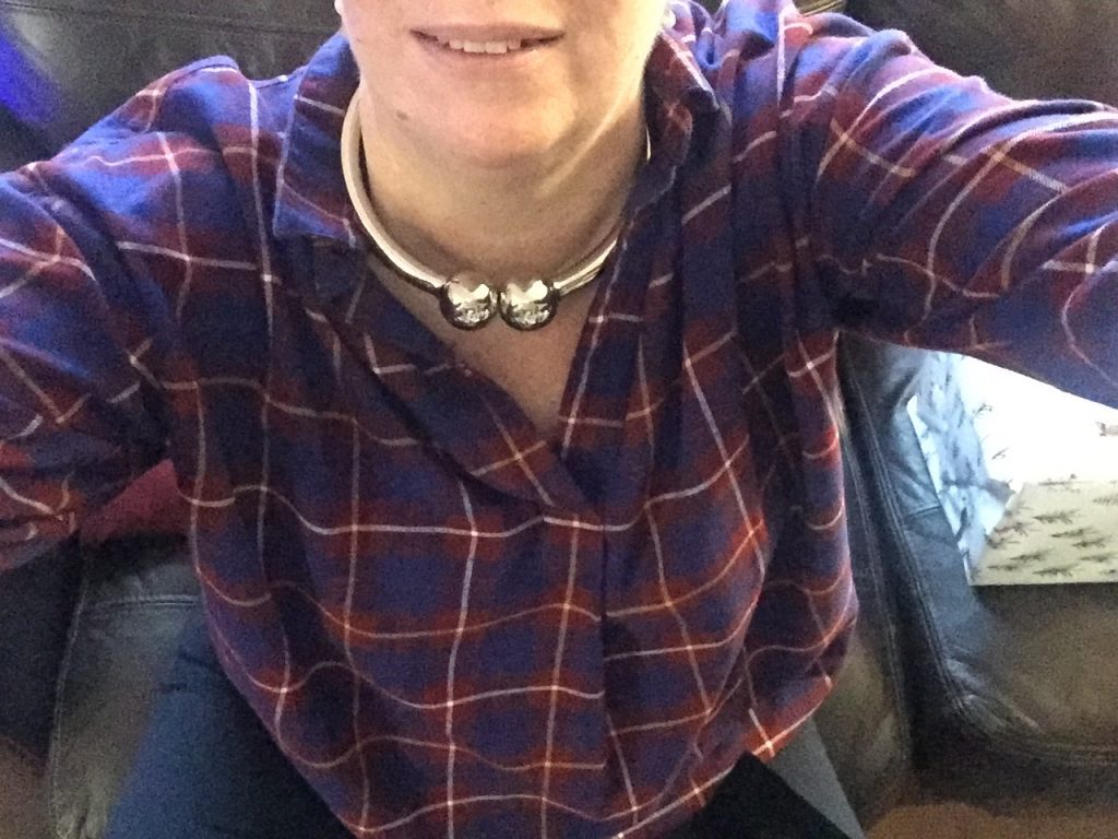 Mme wearing a checked shirt and sporting a heavy silver coloured collar. 