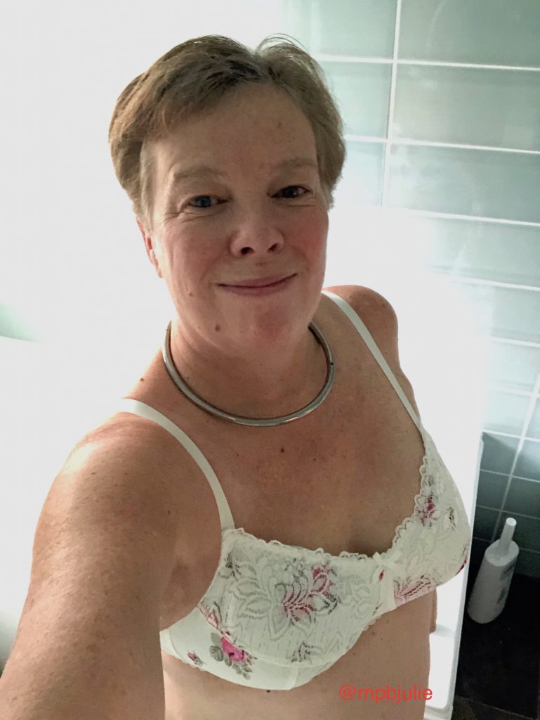 I'm in the bathroom wearing a white bra with pink roses, a collar and a smile!