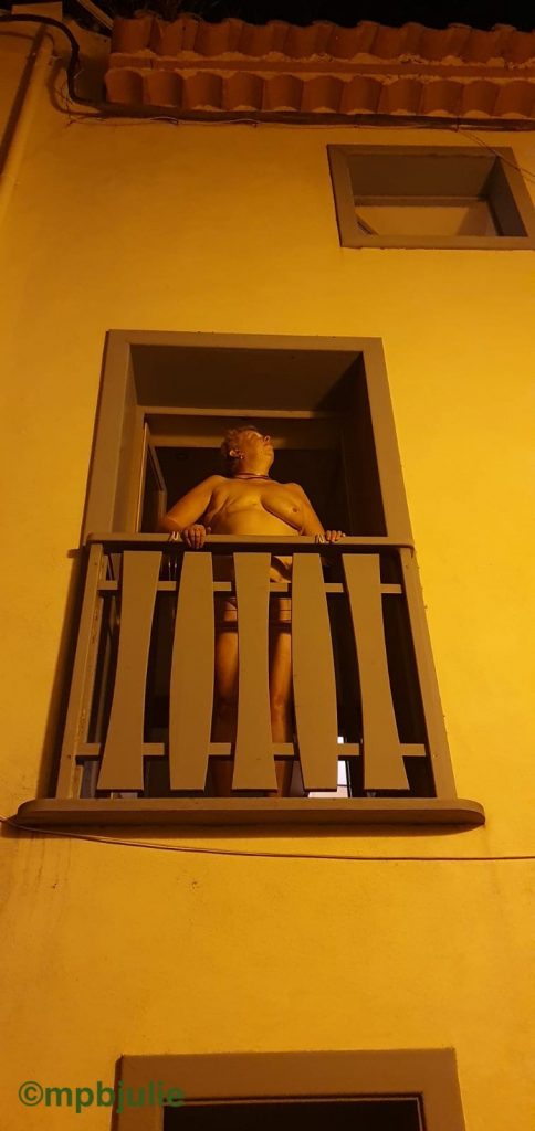 I am standing at the tall open window naked. It is night time. In front of me is a wooden railing. 