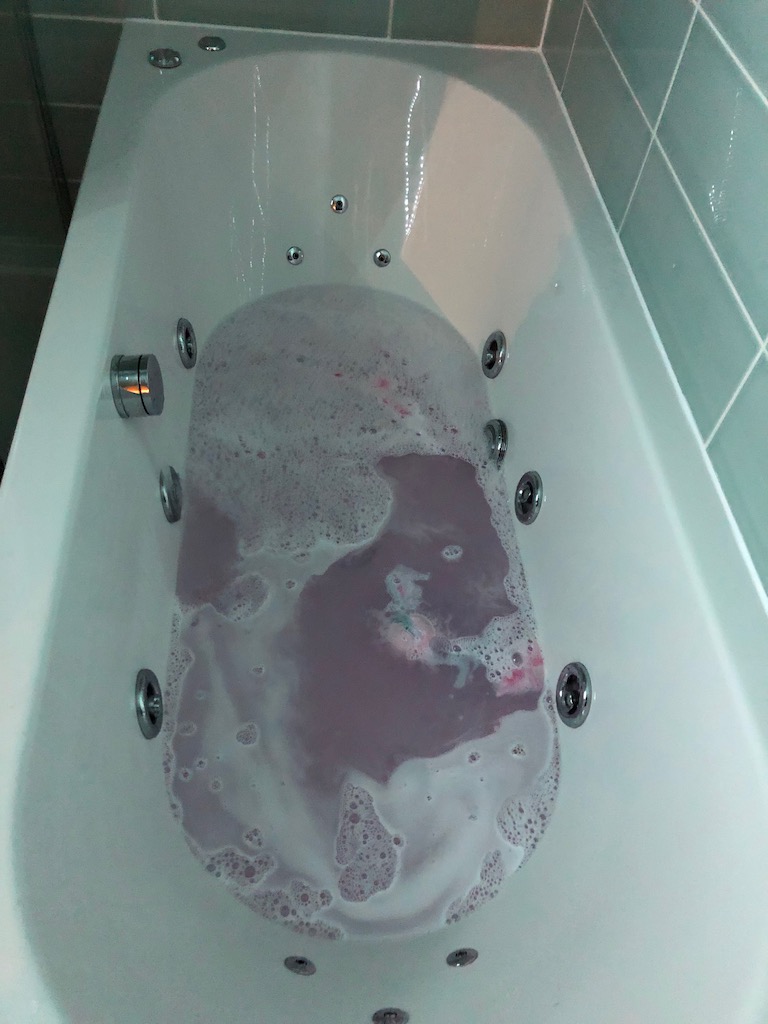 The bath filling. The water is pink and the bath bomb is fizzing