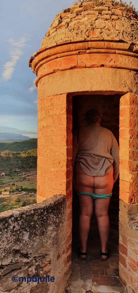 I'm standing in a lookout turret of a castle, showing my bum. Ypi can see my cardigan, knickers, bum, legs  and sandals. 