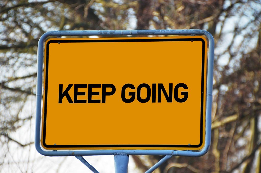 A sign saying Keep Going. Orange back ground and black writing. 