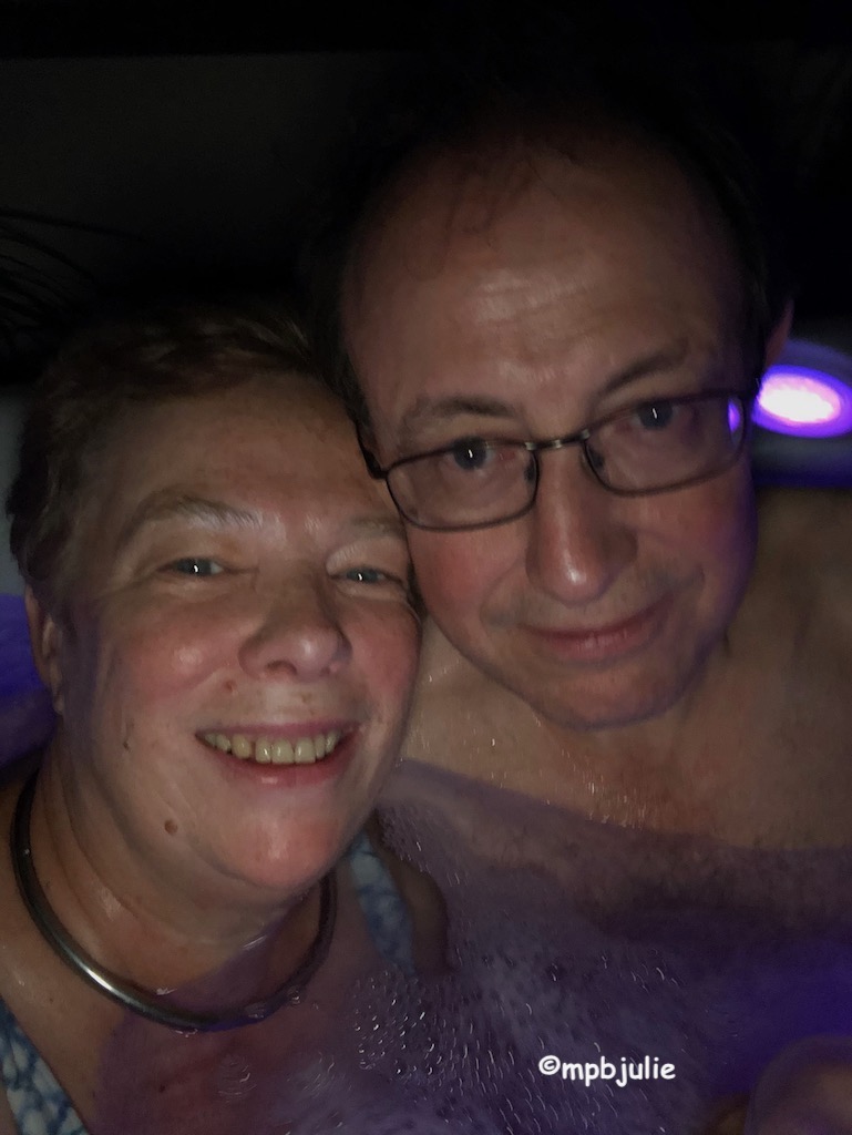 Master and I are in a hot tub at night. You can see our happy faces, the water and down to our chests. I'm wearing a blue and white swimsuit.