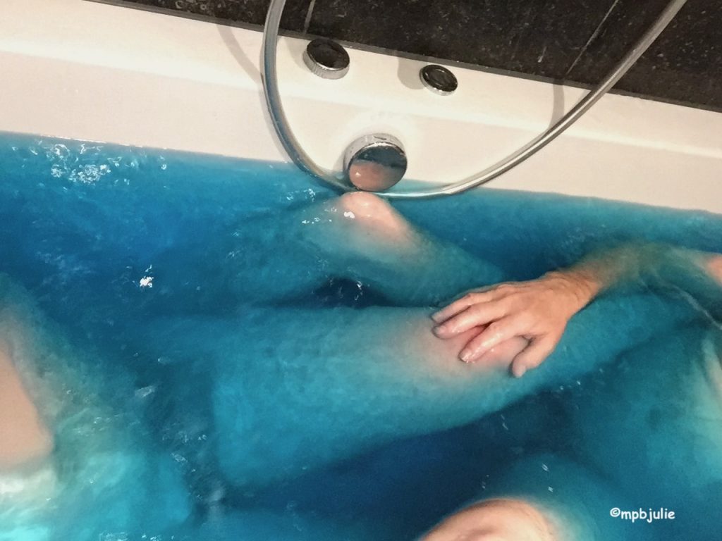 A photo of us in a bath of blue water. you can see one of my legs and one of his. Mine are about twice the size. Plus a little of our abdomens and one of his hands. An arrangement of arms and legs!