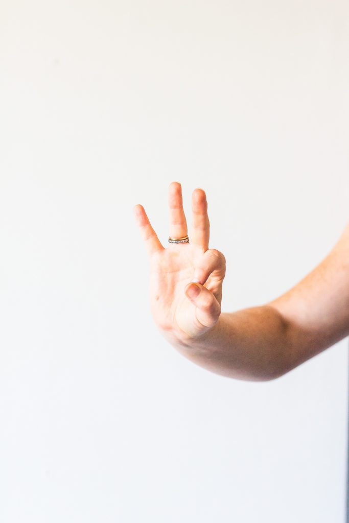 Someone is holding up 3 fingers. The index finger and thumb are in the shape of a 0