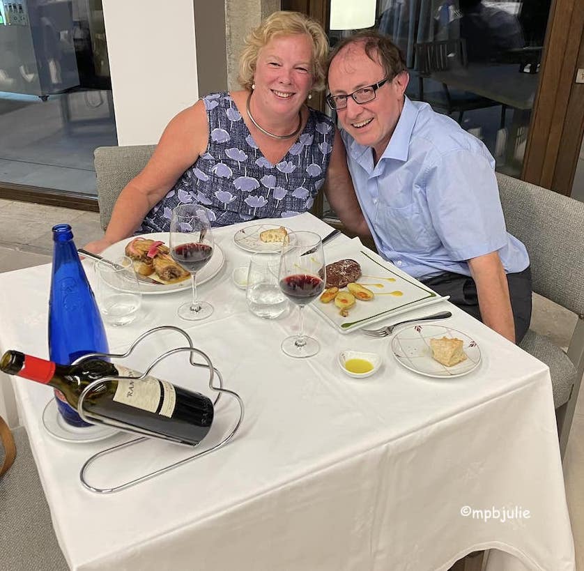 We are sitting at. 2 corners of a table eating dinner outside a restaurant in summer. We are in Spain on honeymoon. 