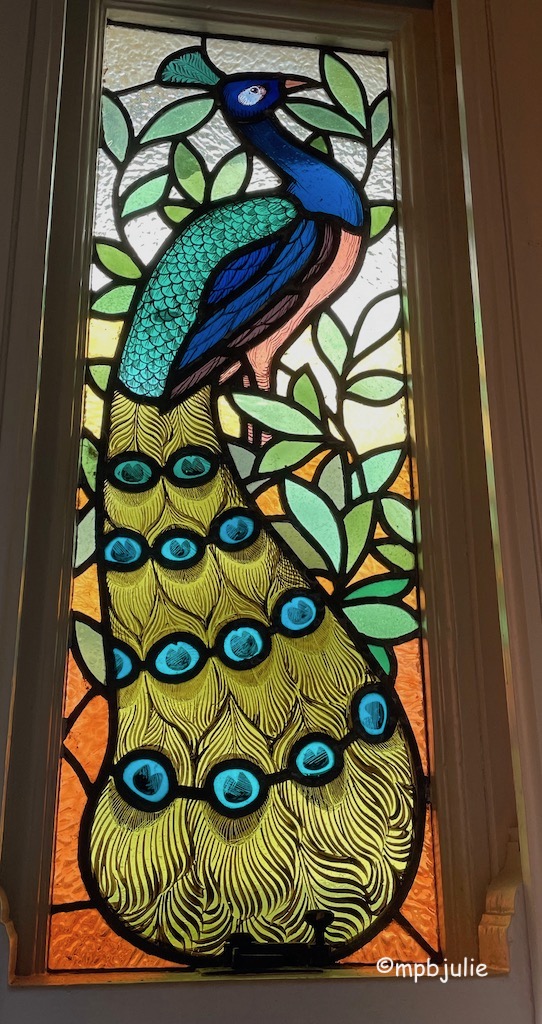 A stained glass window with a peacock image 