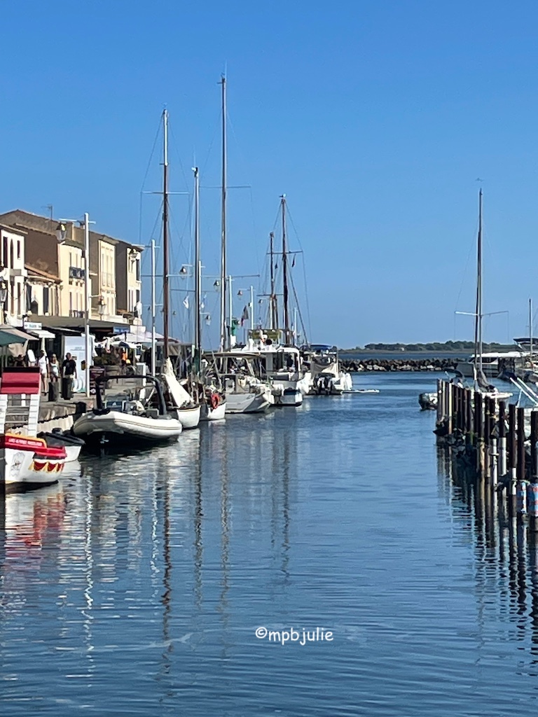 Harbour area, a line of boats and buildings to the left. Entrance / Exit of harbour to right