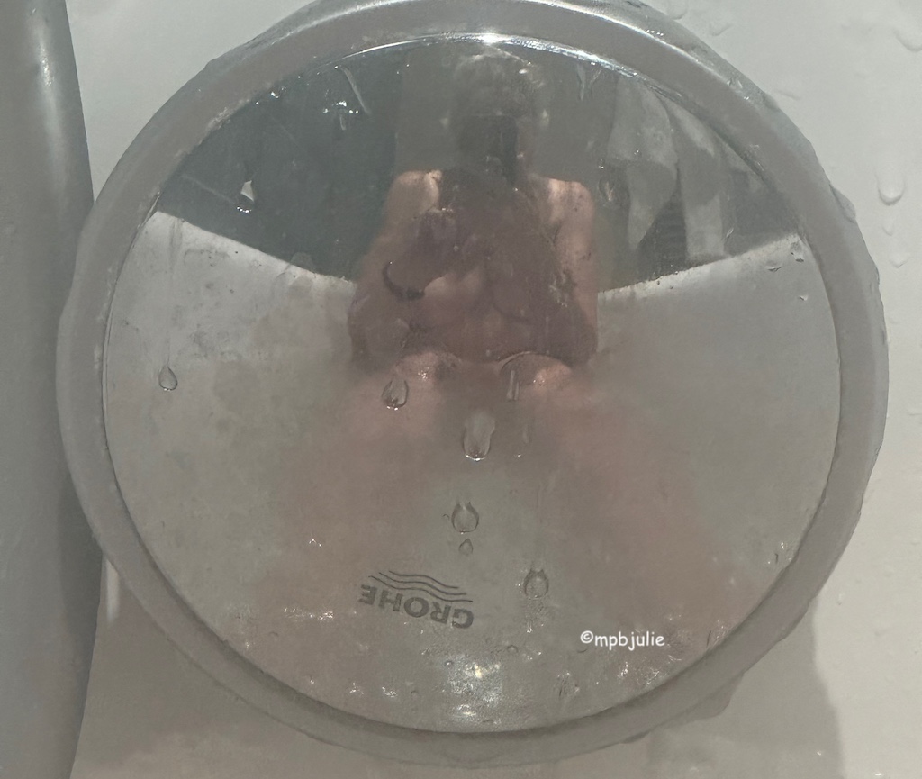 I'm sitting in a hotel bath with a mirrored silver dial under which the. water flows. This has enabled me to photograph myself in. the bath. A mirror image with a difference you. could say. I'm naked and you. can see my. body but not may face since that's hidden by my phone.