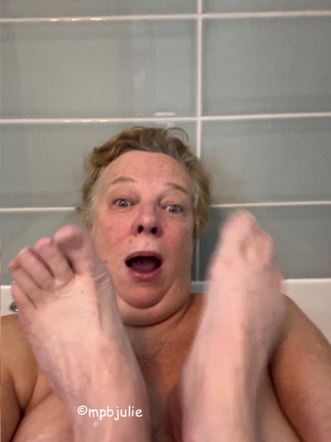 I'm looking startled, open mouthed. G's feet are either side of my face.  We're either end of the bath and my face and a bit of my arms and boobs plus his feet are all you can see.